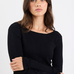Woman wearing a black sweater and blue jeans against a white background
