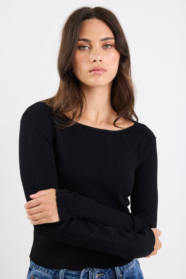 Woman wearing a black sweater and blue jeans against a white background