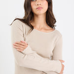 Woman wearing a beige sweater and blue jeans against a white background