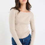 Woman wearing a beige sweater and blue jeans on a white background