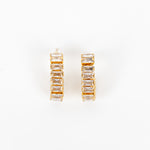 A pair of gold hoop earrings with rectangular clear crystals, displayed on a clean white background.