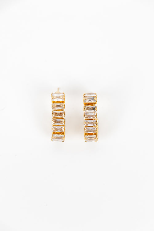 A pair of gold hoop earrings with rectangular clear crystals, displayed on a clean white background.