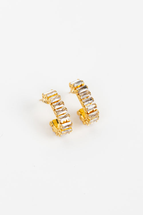 A pair of gold hoop earrings embellished with clear rectangular baguette crystals, displayed on a clean white background.
