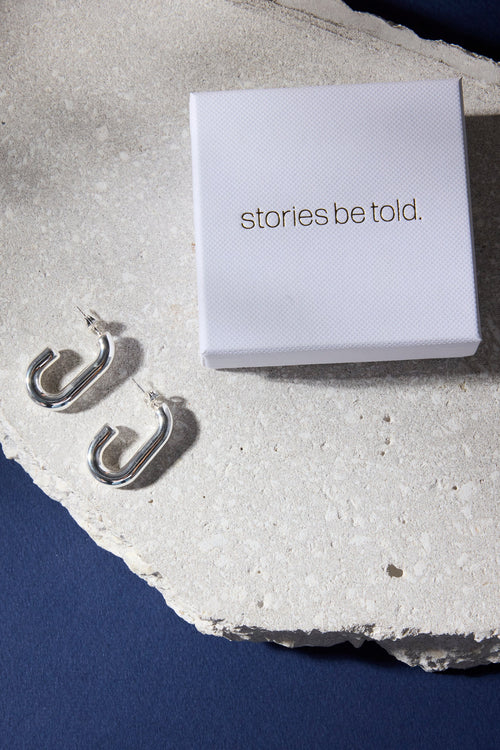 White box with 'stories be told' text on a textured stone surface