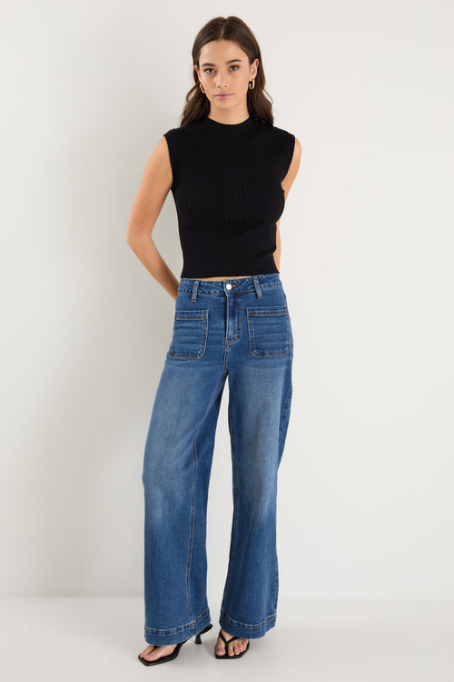 Model wears a black rib knit top with dark blue jeans