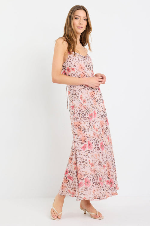 Woman wearing a strappy maxi dress in soft georgette with a floral and animal print blend, bias cut design, and flowing silhouette.