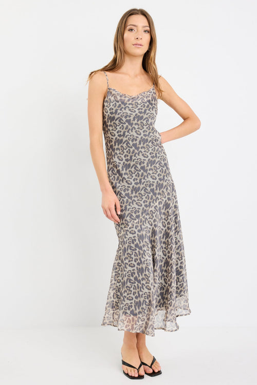 Woman wearing a leopard print strappy maxi dress in lightweight georgette with a bias cut and flowing silhouette.