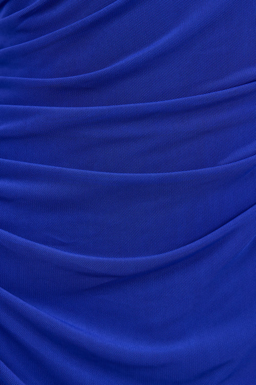 A close-up of draped royal blue fabric with soft folds and a fine woven texture.