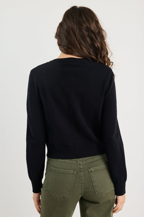 Person wearing a black sweater and green pants on a white background