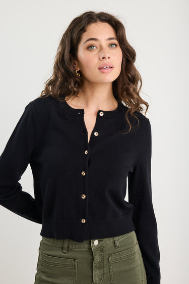 Woman wearing a black cardigan with a plain background