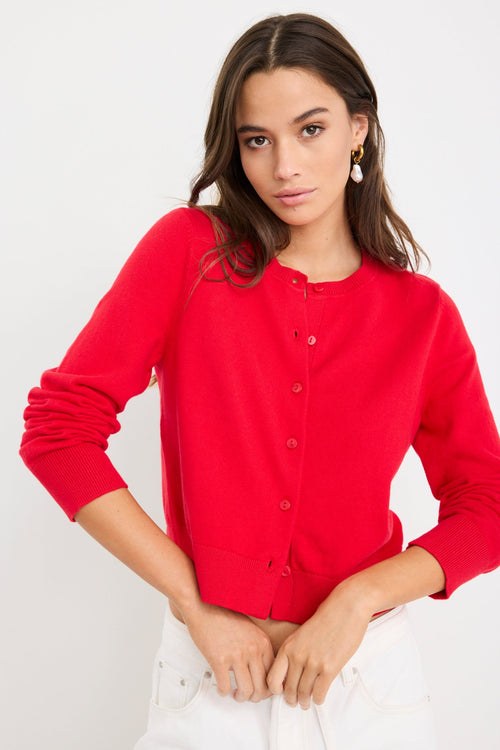 Woman wearing a cherry red crewneck cardigan with long sleeves and button-front closure, styled with denim jeans.