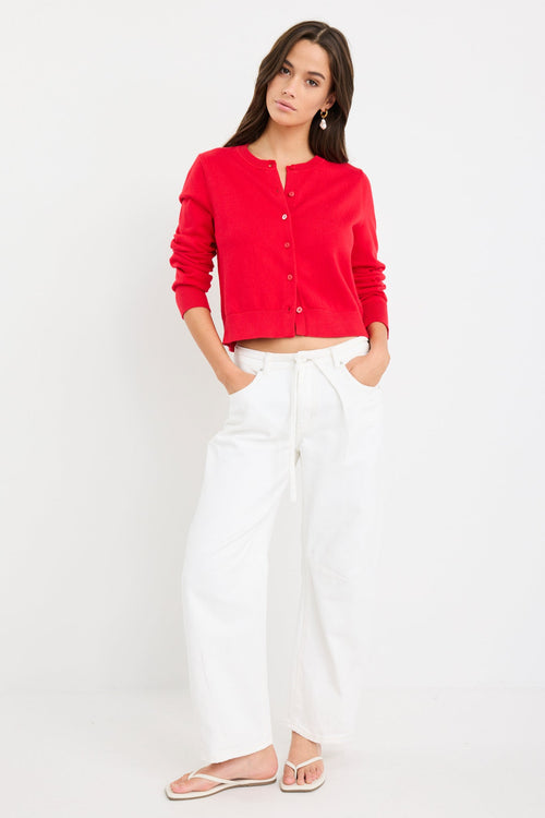 Woman wearing a cherry red crewneck cardigan with long sleeves and button-front closure, styled with denim jeans.