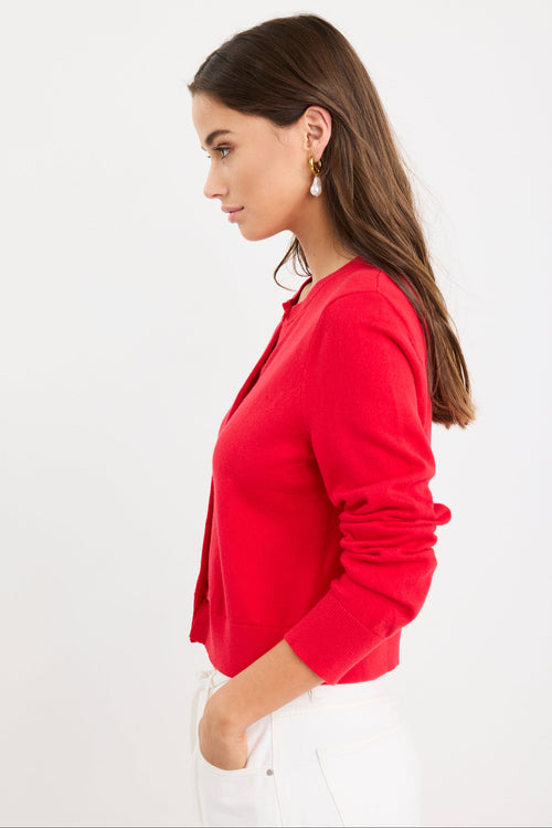 Woman wearing a cherry red crewneck cardigan with long sleeves and button-front closure, styled with denim jeans.