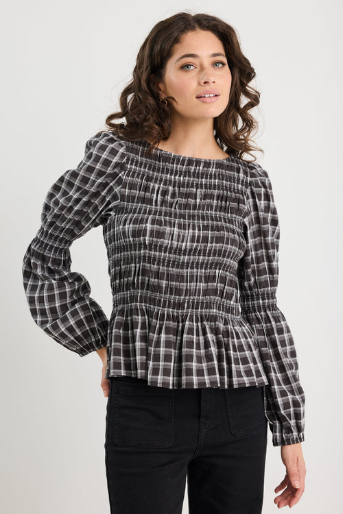 Woman wearing a black and white checkered blouse with puffed sleeves on a white background