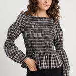 Woman wearing a black and white checkered blouse with a plain background