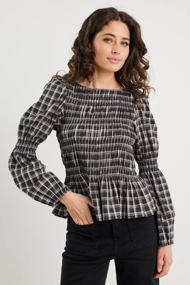 Woman wearing a black and white checkered blouse with a plain background