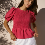 model wearing raspberry shirred top