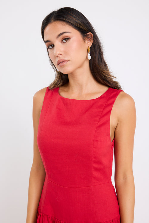 Woman wearing a sleeveless cherry red midi dress with a fitted bodice and gathered skirt, paired with neutral flats.