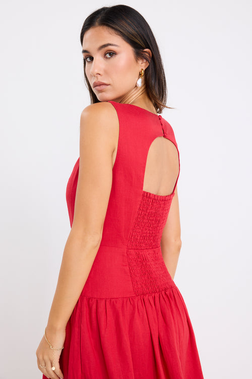 Woman wearing a sleeveless cherry red midi dress with a fitted bodice and gathered skirt, paired with neutral flats.