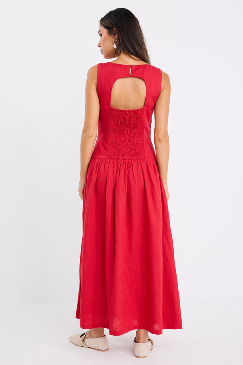 Woman wearing a sleeveless cherry red midi dress with a fitted bodice and gathered skirt, paired with neutral flats.