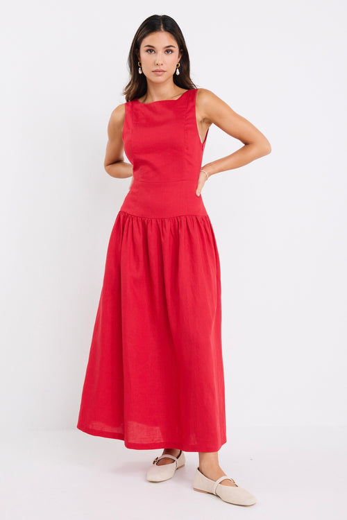Woman wearing a sleeveless cherry red midi dress with a fitted bodice and gathered skirt, paired with neutral flats.