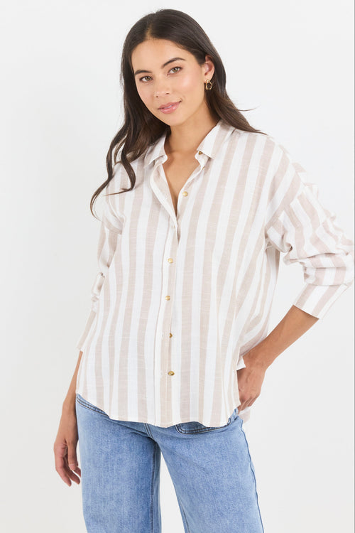 Woman wearing a white and beige striped shirt with blue jeans on a white background