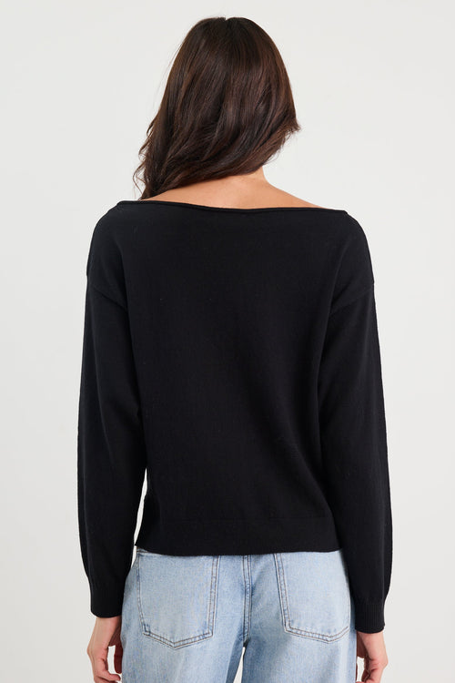 Person wearing a black long-sleeve top and light blue jeans on a white background
