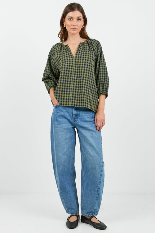 Woman wearing a green checkered blouse and blue jeans on a white background