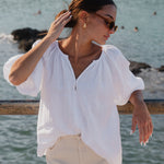 model wears white linen top and ecru mini skirt