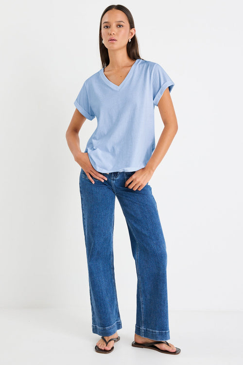 Woman wearing a light blue t-shirt and dark blue jeans on a white background