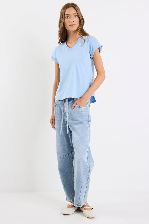 Woman wearing a light blue t-shirt and light blue jeans on a white background