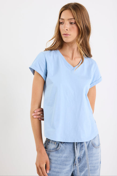 Woman wearing a light blue t-shirt and jeans on a white background