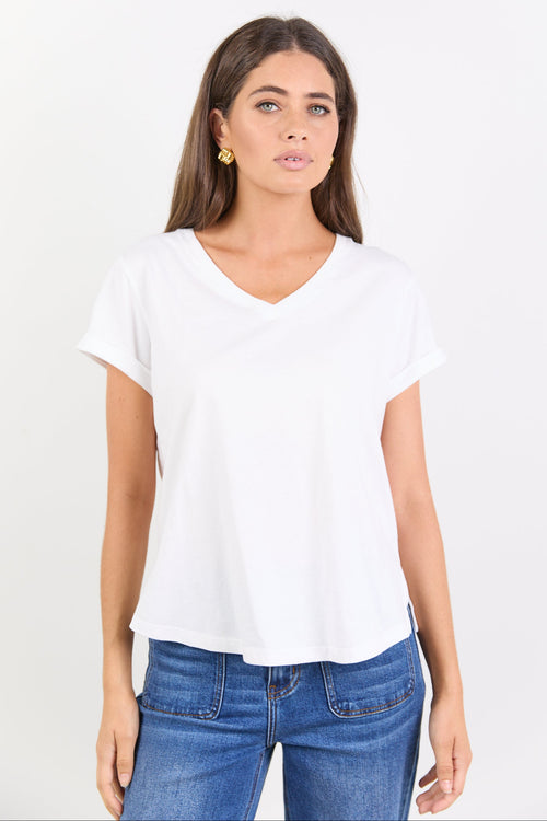 Woman wearing a white t-shirt and blue jeans on a plain background