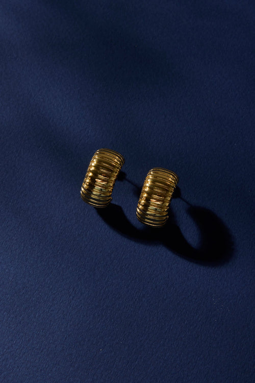 Gold textured cufflinks on a dark blue fabric background