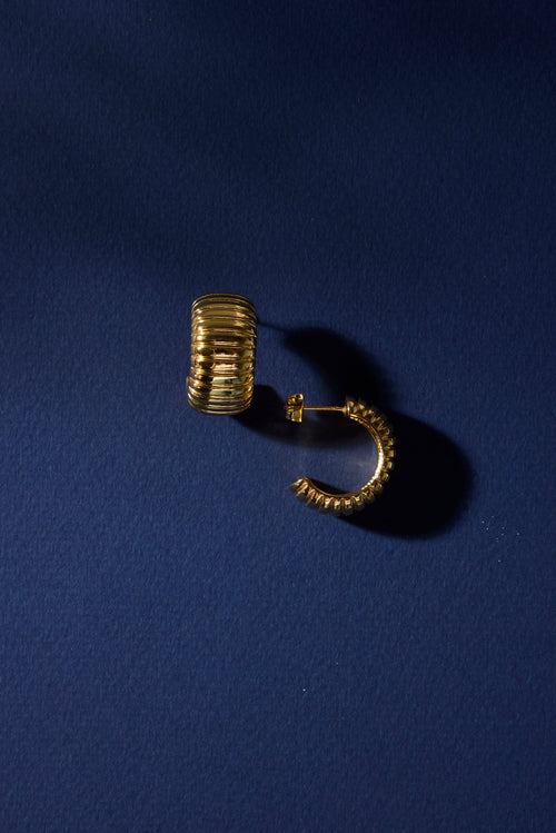 Gold hoop earring on a dark blue background
