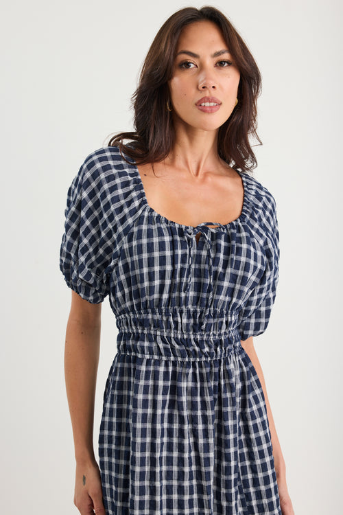 Woman wearing a blue and white checkered dress on a white background