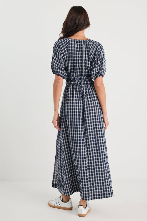 Woman wearing a blue and white checkered dress on a white background