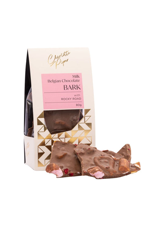 A package of Chocolate Pèpé Belgian Chocolate Bark with Rocky Road, shown with several pieces of milk chocolate bark in front of the box on a white background.