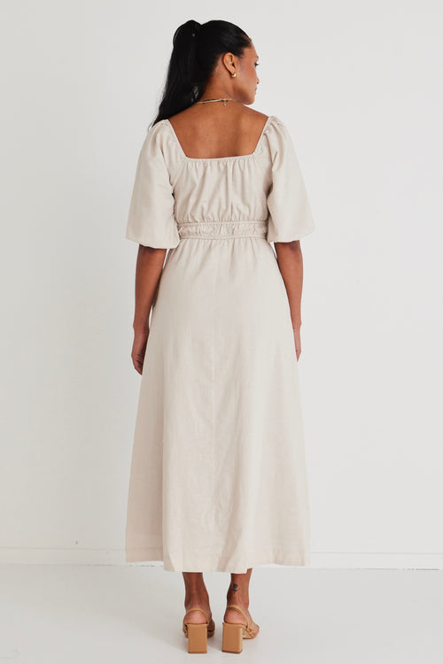 Model wears a linen  midi dress with a slit in the leg. 