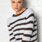 Woman wearing a brown and white striped sweater against a light background