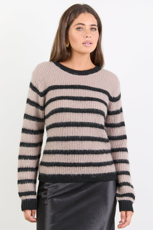 Woman wearing a beige and black striped sweater on a white background