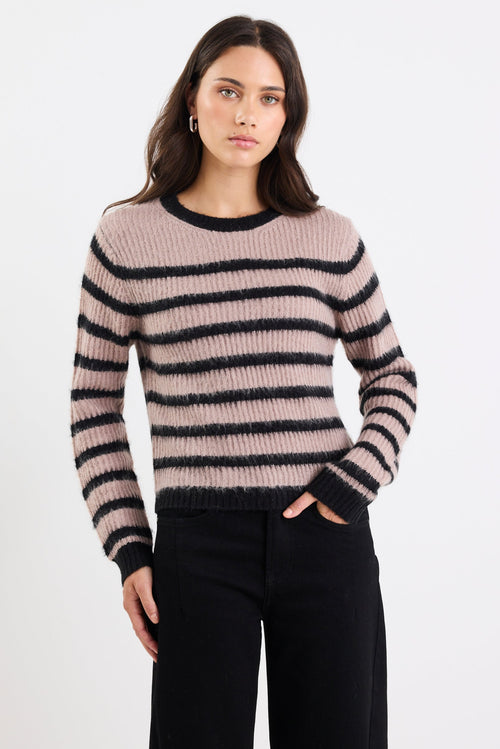 Woman wearing a striped sweater and black pants on a white background