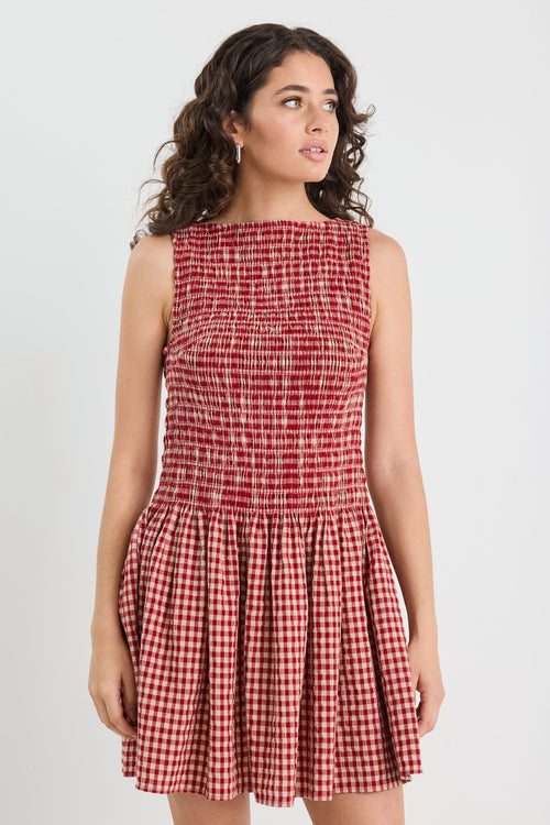 Woman wearing a red checkered dress against a white background