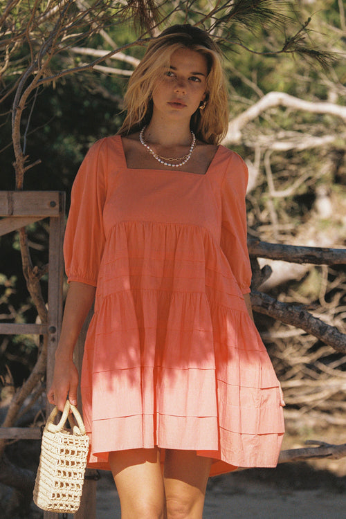 model wears a orange mini dress