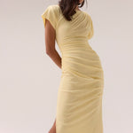 Lemon yellow maxi dress with short sleeves, ruched side detailing, high side slit, and a straight neckline, worn by a model in silver heels against a neutral background.