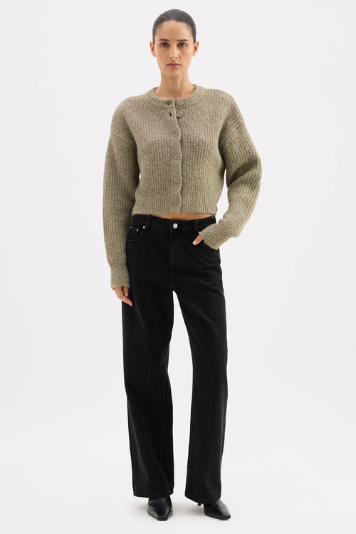 Woman wearing a textured cardigan and black pants on a white background