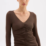 Woman wearing a brown long-sleeve top with a V-neck on a white background