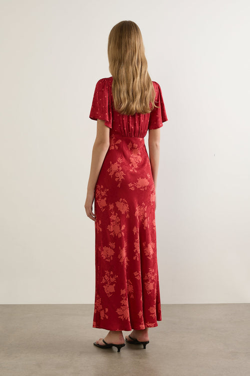 Woman wearing a red floral dress against a white background