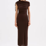 A woman modeling a dark brown off-the-shoulder midi dress with a draped neckline and side tie detail, paired with dark brown heeled sandals, against a plain white studio background.