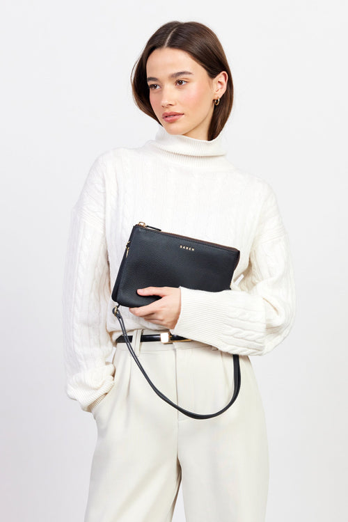 Woman holding a black clutch bag against a white background